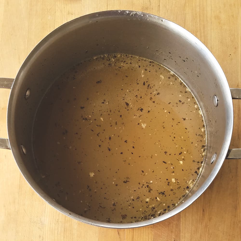 Strained homemade chicken stock in pot