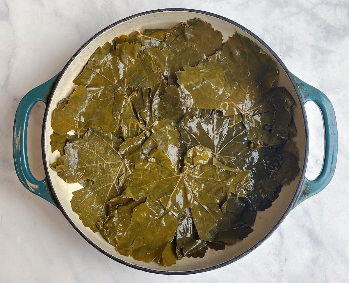 Grape leaves lining large enameled skillet.