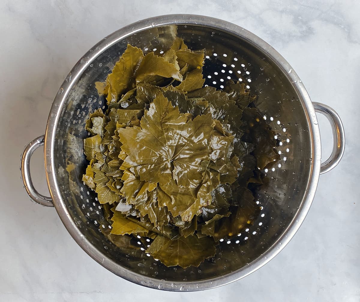 Grape leaves in metal colander.