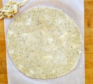 herb pie crust rolled out on parchment