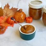 small ramakin of pumpkin butter, with fall decor and jars of pumpkin butter in the background.