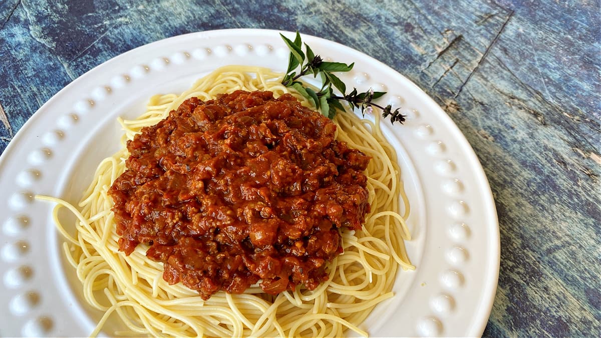 Spaghetti sauce plated, served over untossed thin spaghetti noodles. 