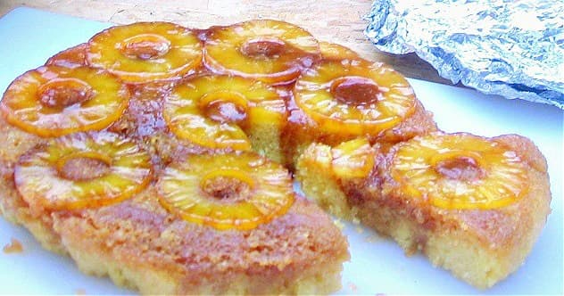 Close-up of cooked pineapple upside-down cake, with one slice cut out. 