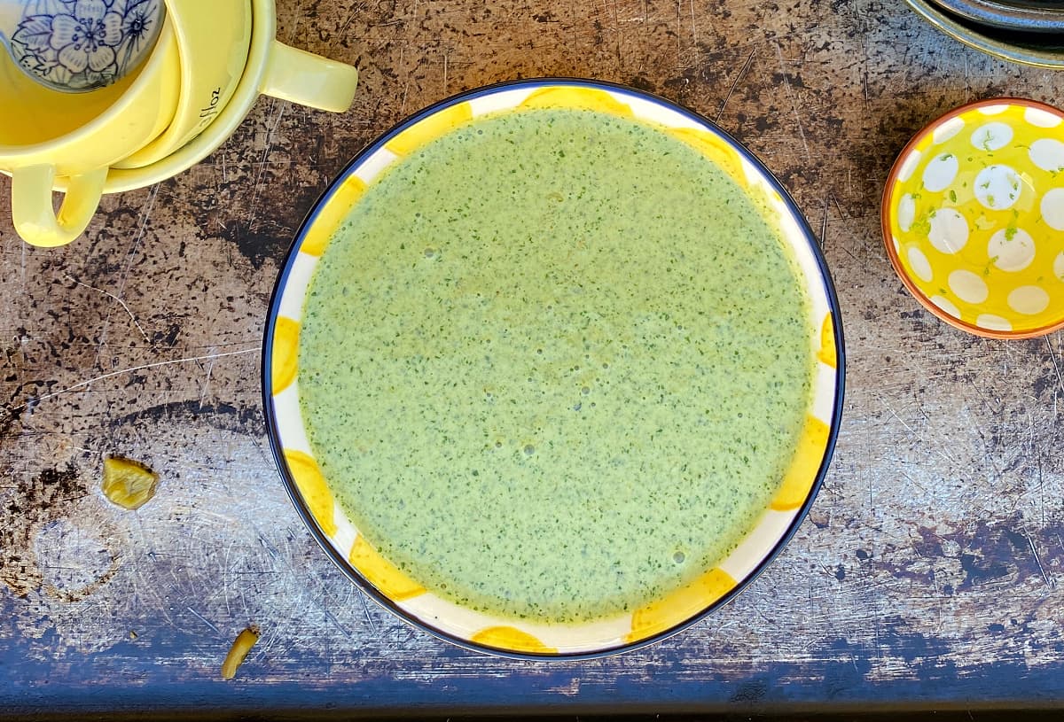 Creamy green dressing on a bowl. Smaller, empty ingredients bowls on the side.