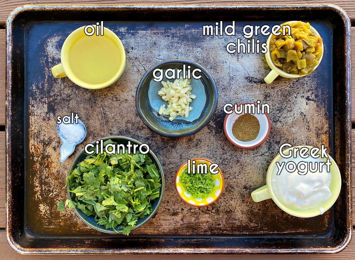 Dressing ingredients on a tray, labeled: oil, mild green chilis, cilantro, lime, Greek yogurt, cumin, salt.