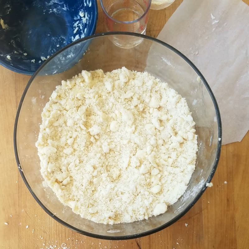 butter added to pie dough mix in a large glass mixing bowl.