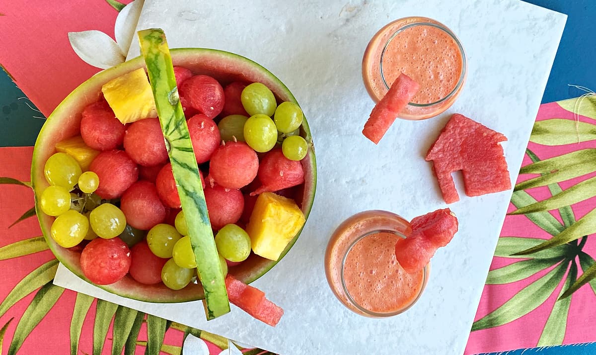 Overhead shot of watermelon basket and two glasses of watermelon drink.