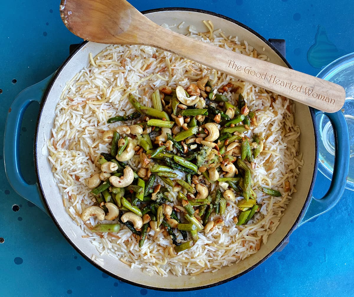 Cashew and asparagus mixture added to rice mix in skillet, but not yet mixed together. 