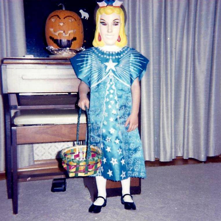 Me, masked and dressed in a late 1960s Cinderella costume for Halloween. Holding an Easter basket. 