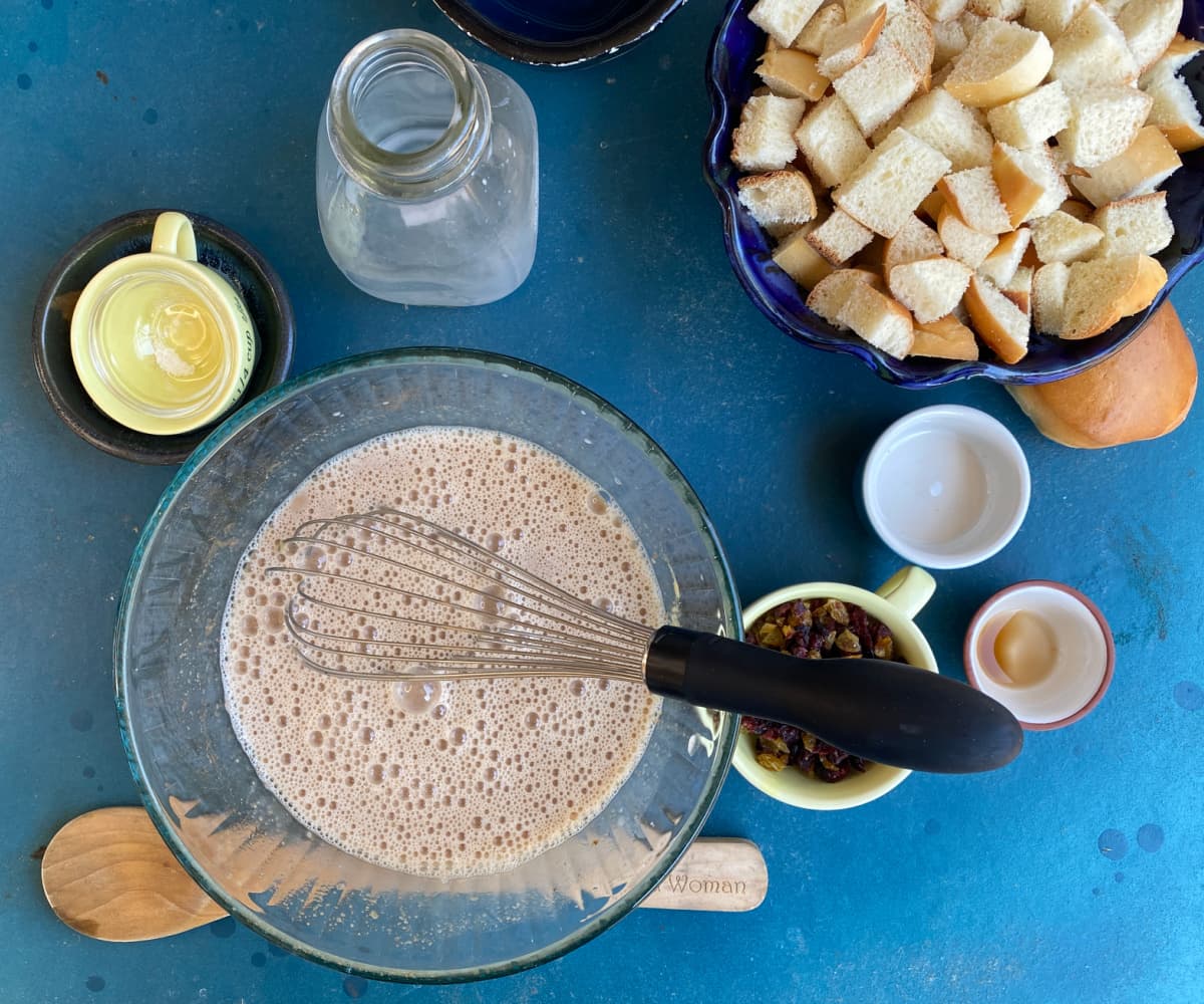 Whisking milk into ingredients in glass mixing bowl.