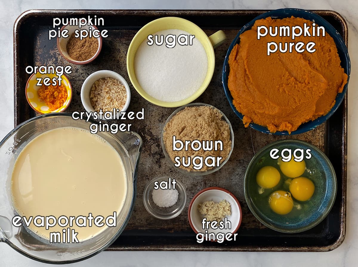 Ginger pumpkin pie ingredients, labeled: pumpkin purre, sugar, pumpkin pie spice, brown sugar, eggs, fresh ginger, crystalized ginger, pumpkin pie spice, orange zest, salt, evaporated milk. 