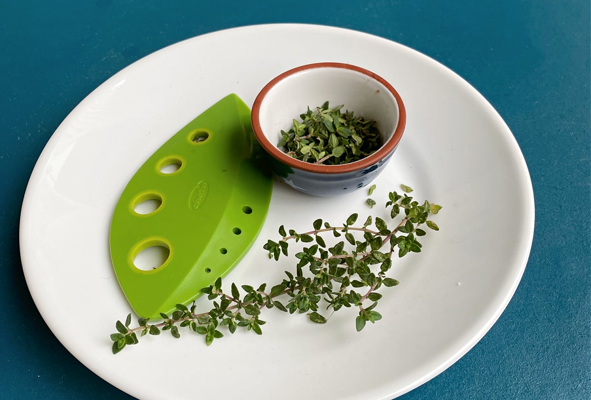 Fresh thyme on plate with herb stem stripper.