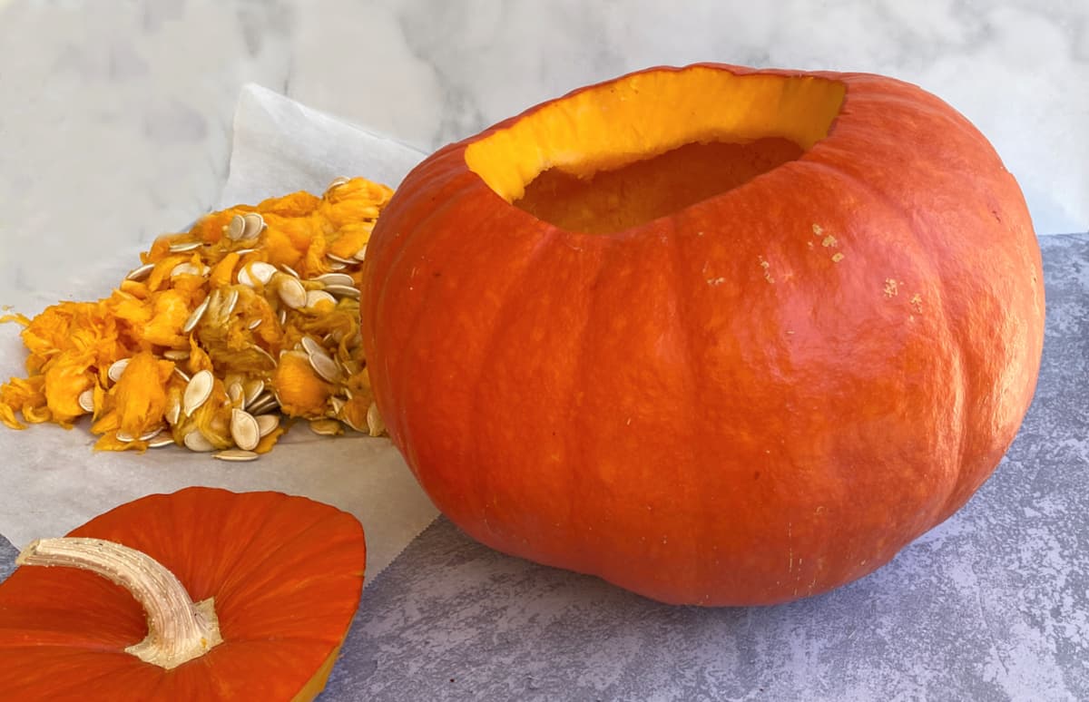 Hollowed out pumpkin with seeds and guts in the background.