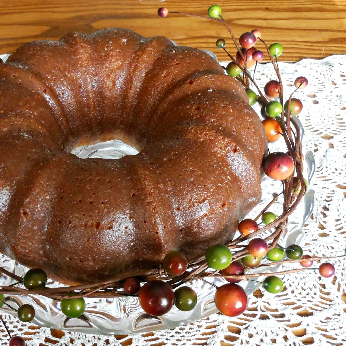 Baked and glazed bundt cake, surrounded with a decorative berry garland.