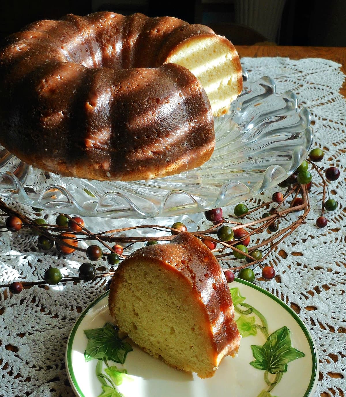 Slice of bundt cake on old fashioned ivy plate, sitting on crocheted tablecloth.