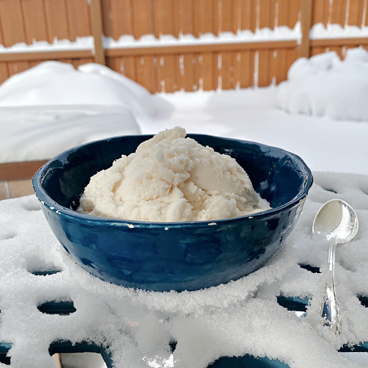 Snow ice cream in a bowl, setting on a snow-covered bistro table.
