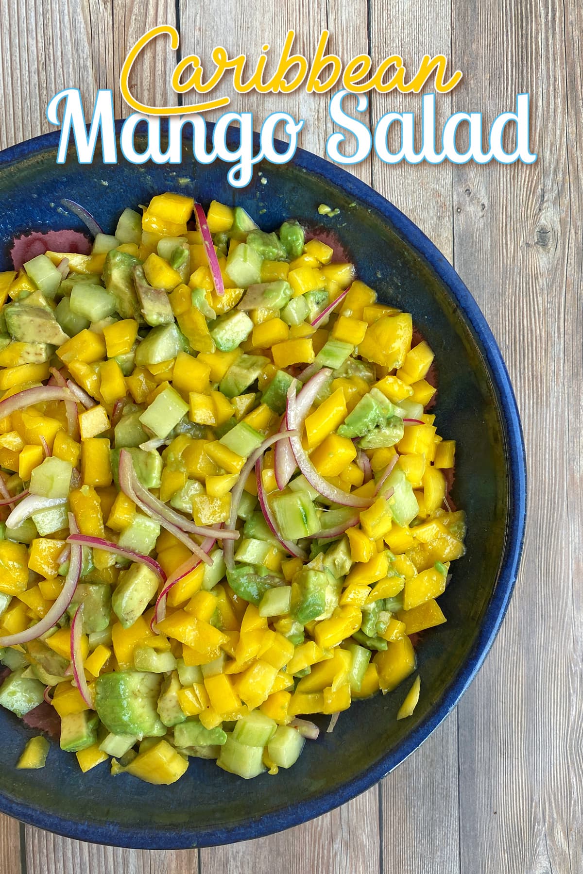 Prepared mango avocado salad in a bowl. Pin overlay reads "Caribbean Mango Salad"