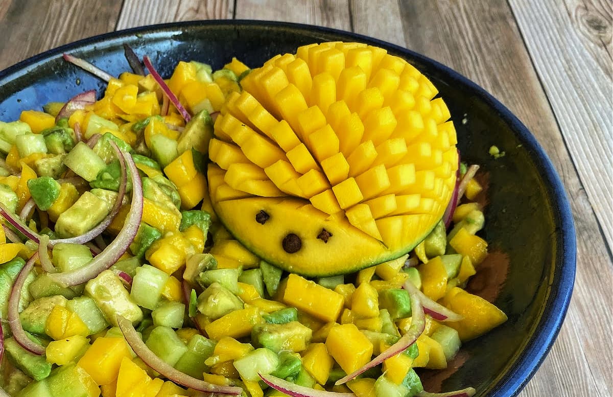 Mango hedgehog on mango salad in bowl.