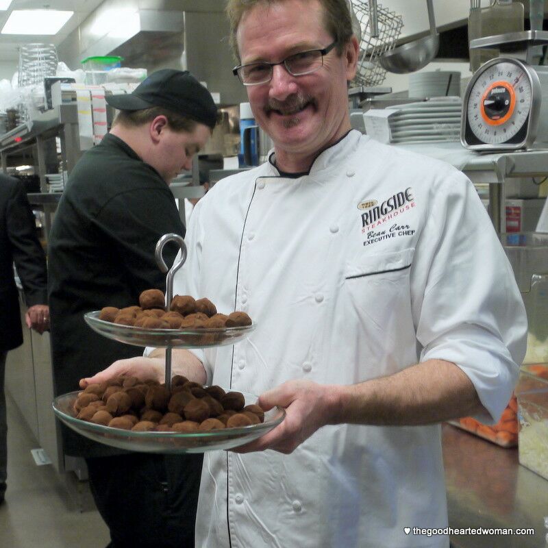 Chef holding a tiered tray of handmade chocolate truffles. 