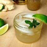 45-degree shot of Classic Whiskey Ginger with Lime is a short Mason jar, garnished with mint sprig and lime wedge.