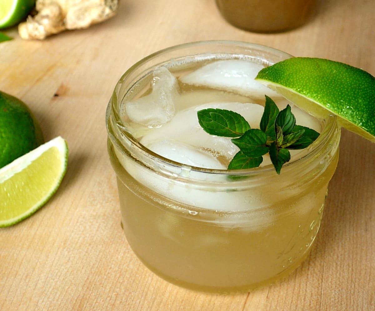 Whiskey ginger in a small mason jar, garnished with a lime slice and fresh mint.