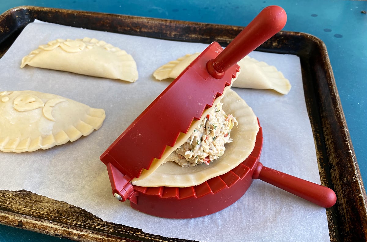 Red pie maker/crimper filled with dough and tuna filling.