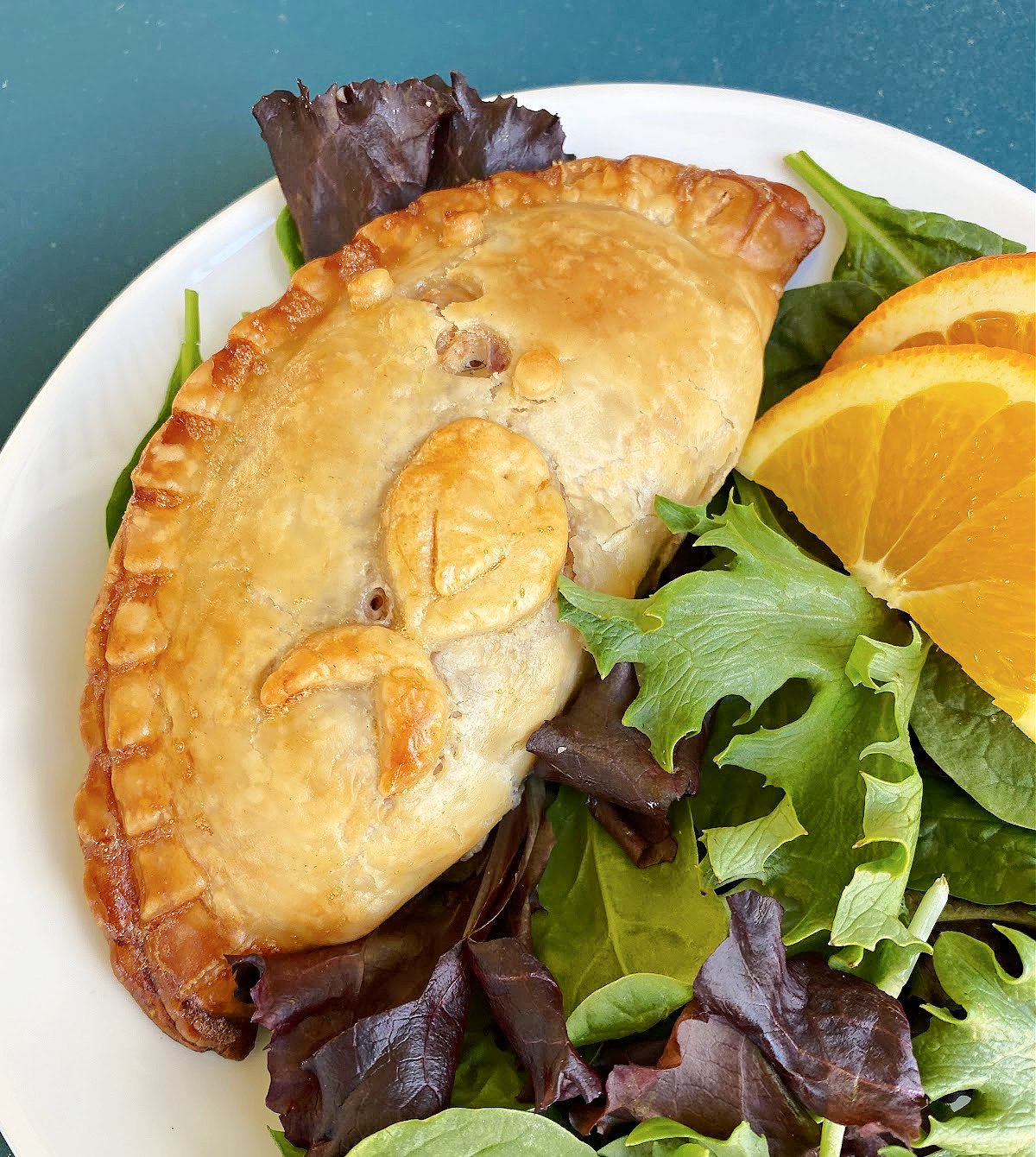 Close-up of tuna pie on plate with salad greens.