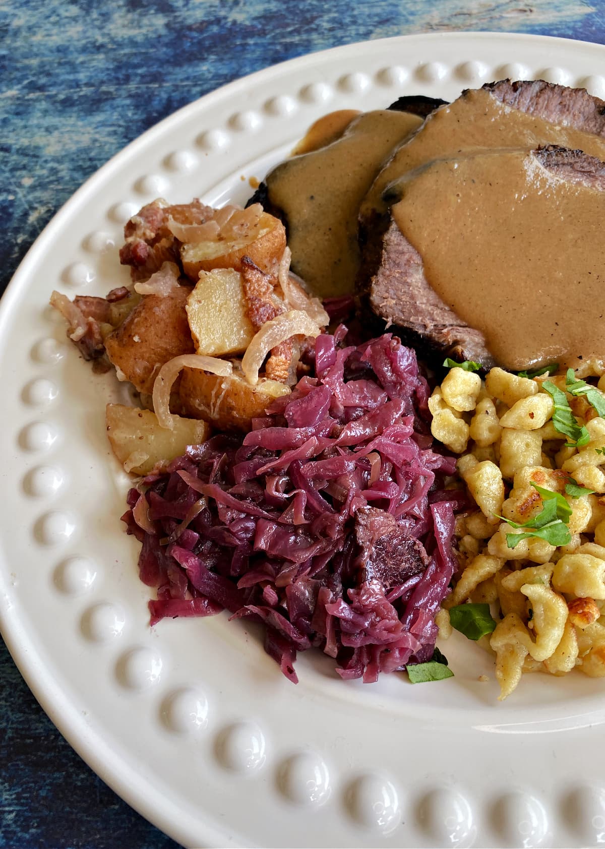 German red cabbage plated with spaetzle, sauerbraten, and german potato salad for Oktoberfest. 
