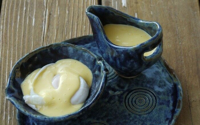 Prepared hollandaise sauce in a small, Asian-inspired pottery bowl and sauce pitcher.  