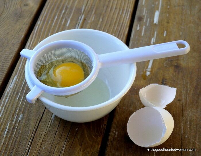 Small sieve with a raw egg in it, over a small prep bowl. 