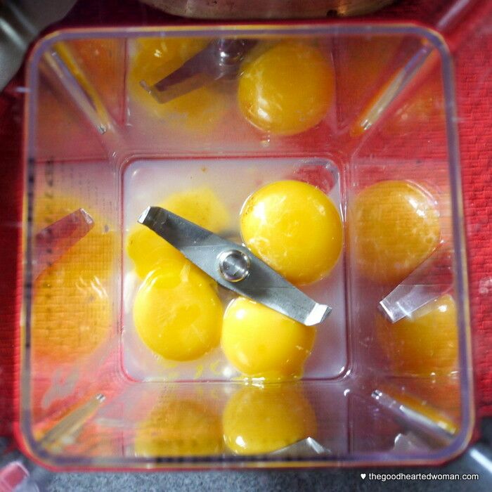 overhead shot of egg yolks and other ingredients in blender cup. 