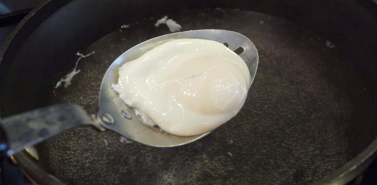 Poached egg on a slotted spoon.