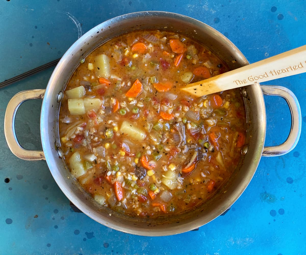 Fully cooked vegetable soup in a soup pot.