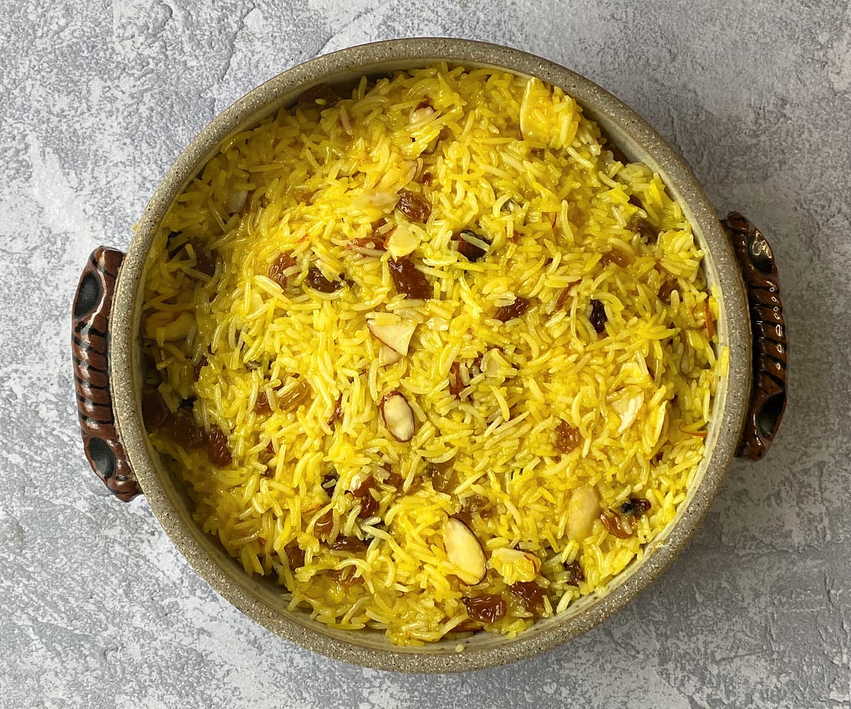 Overhead shot of Sweet Saffron Rice, cooked in a crockery casserole dish, ready to go into the oven.