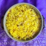 Overhead shot of Sweet Saffron Rice, cooked in a crockery casserole dish, garnished with edible gold leaf.