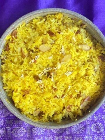 Overhead shot of Sweet Saffron Rice, cooked in a crockery casserole dish, garnished with edible gold leaf.