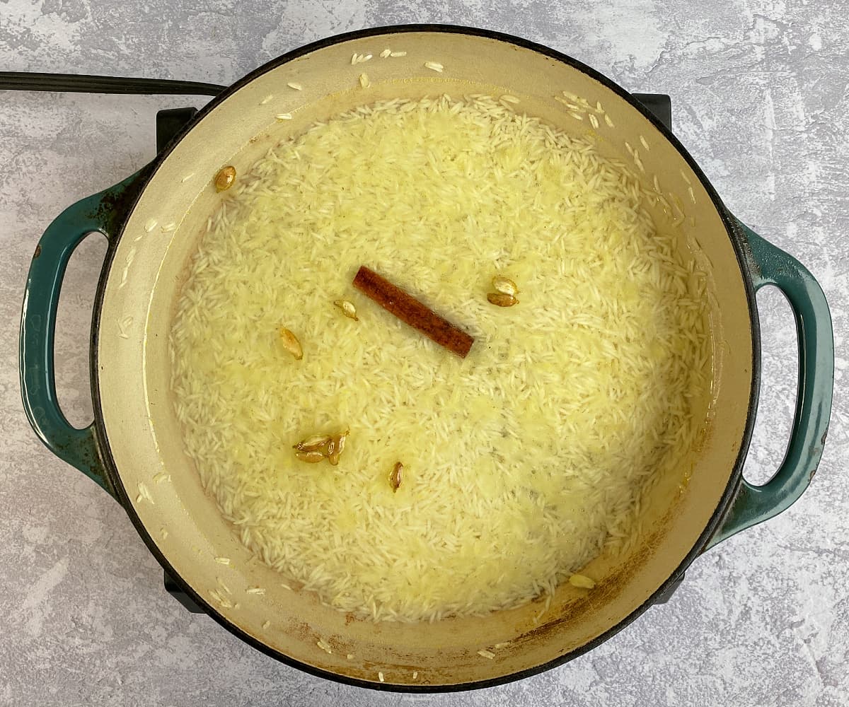Water added to rice and spices in a large skillet.