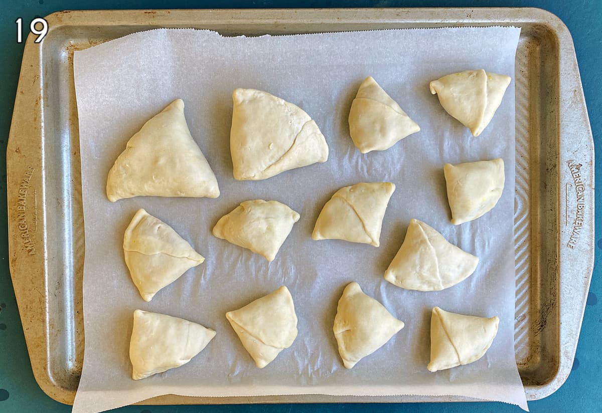 Samosas on a parchemnt-lined baking tray, ready to bake.