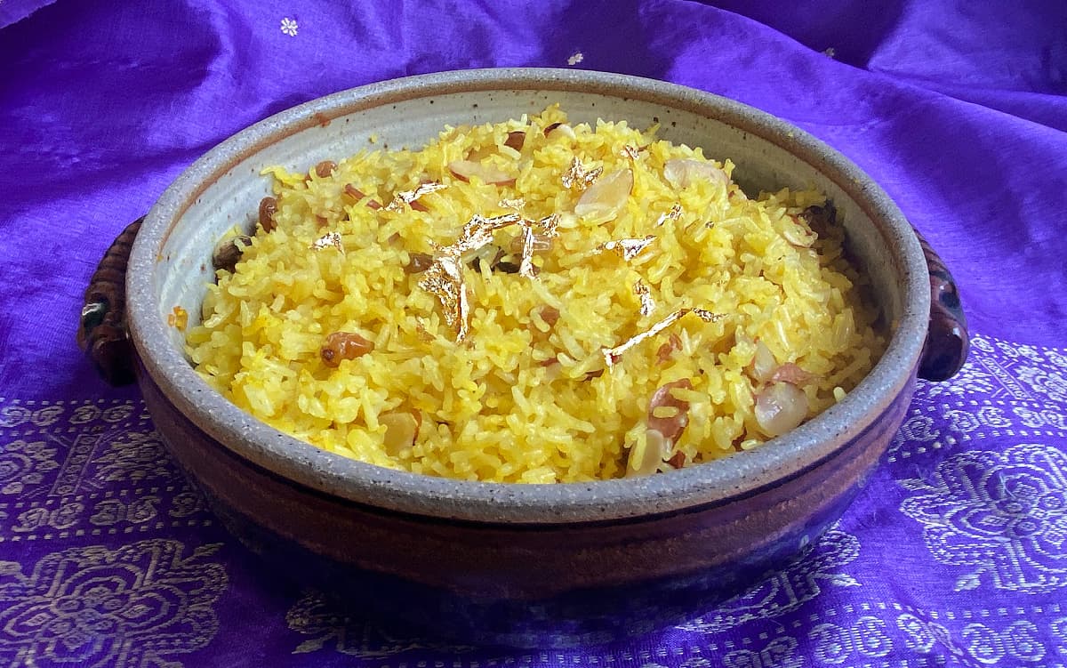 Sweet Saffron Rice, cooked in a crockery casserole dish, garnished with edible gold leaf.