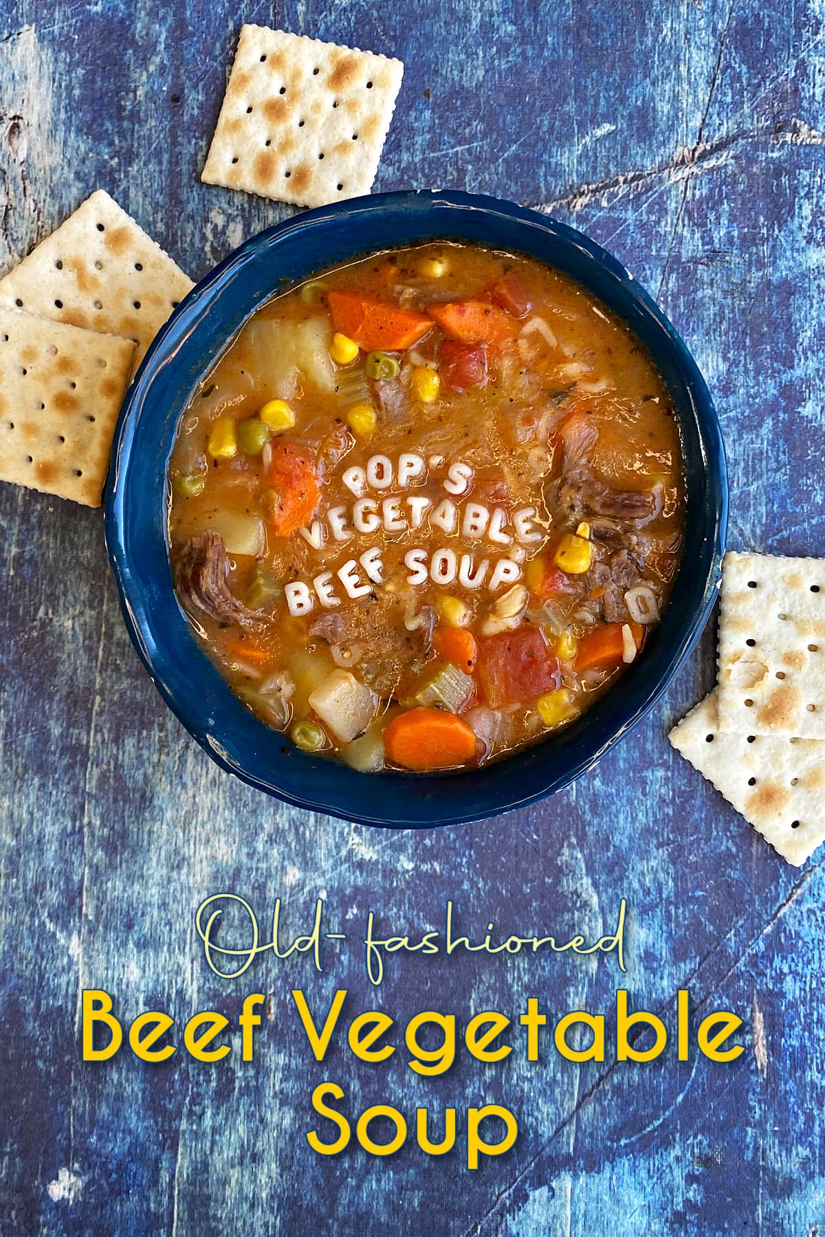 A bowl of vegetable soup, with saltine crackers strewn at the foot of the bowl. Alphabet letters spell out "Pop's Vegetable Beef Soup" across the top of the soup. Pin Text reads: Old-fashioned Beef Vegetable Soup