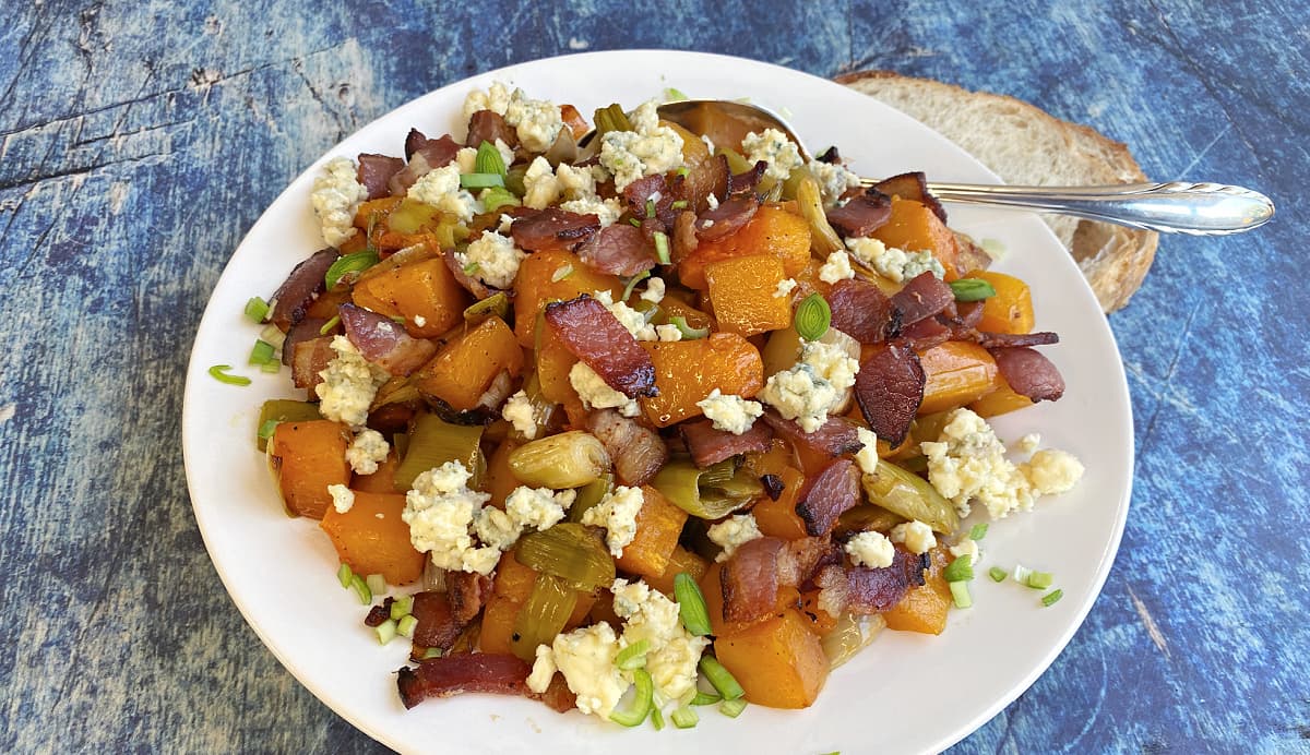 Plate of prepared butternut squash with leeks, bacon, and blue cheese.