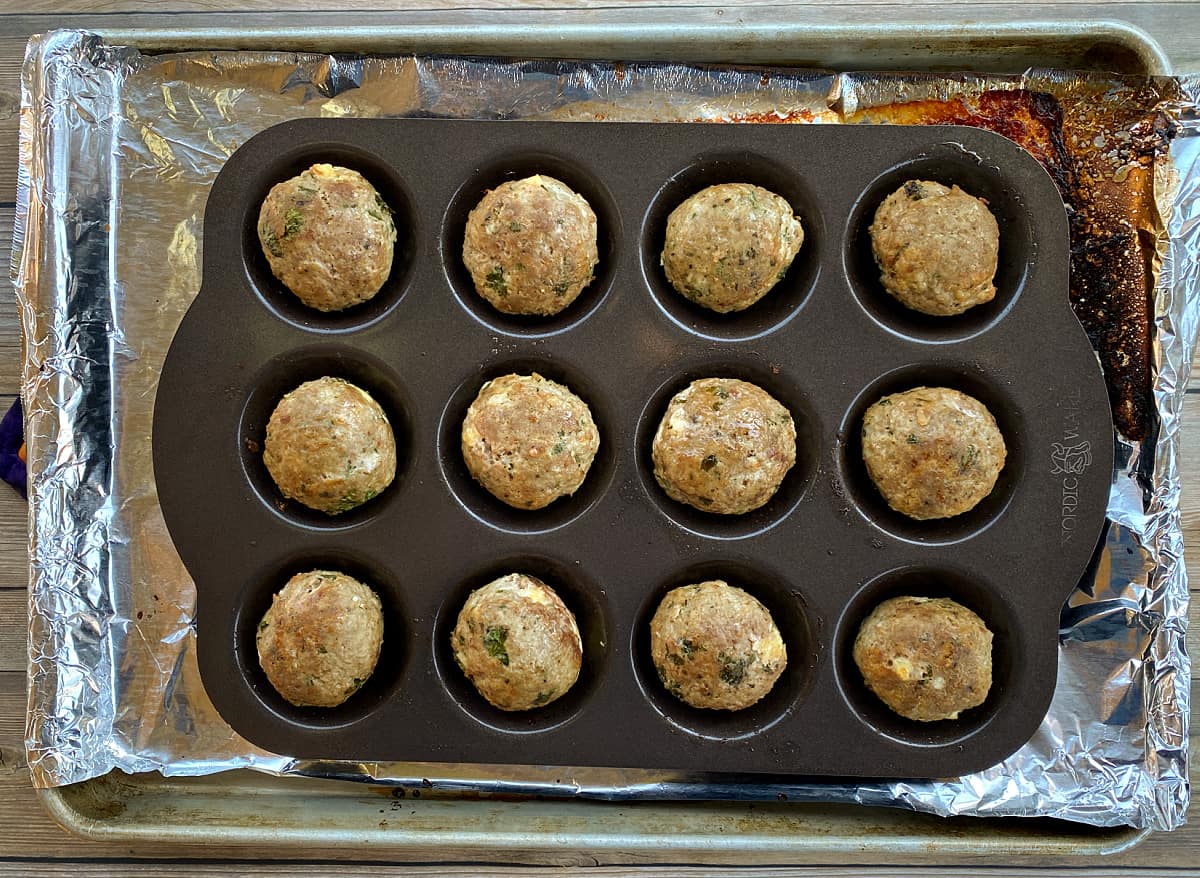 12 baked meatballs in a meatball pan.