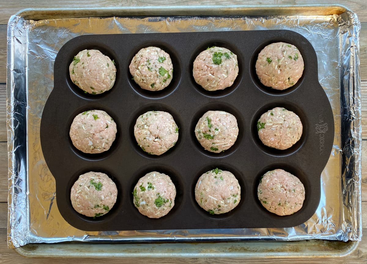12 uncooked meatballs in a pan.