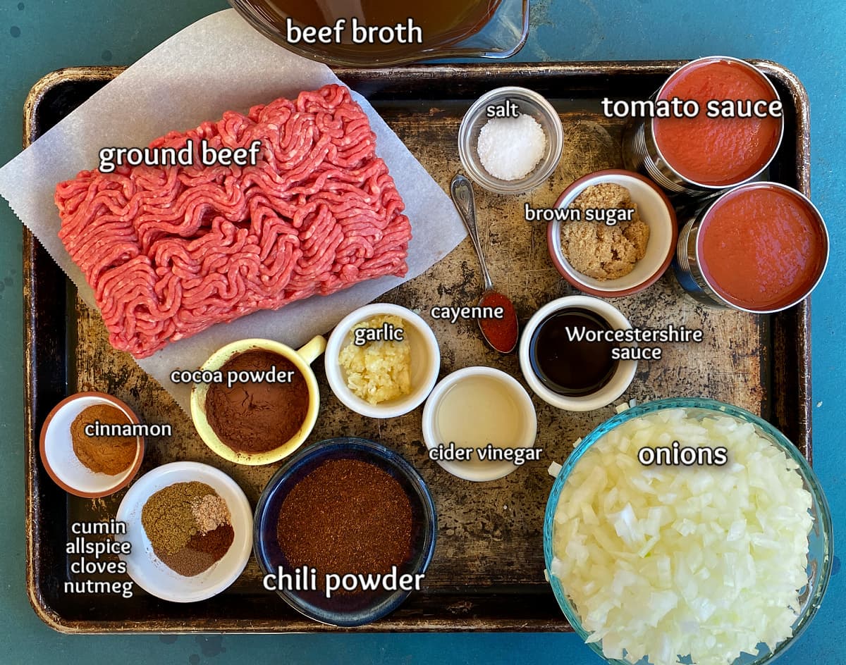 Ingredients for Cincinnati chili displayed in bowls on old baking sheet. 
