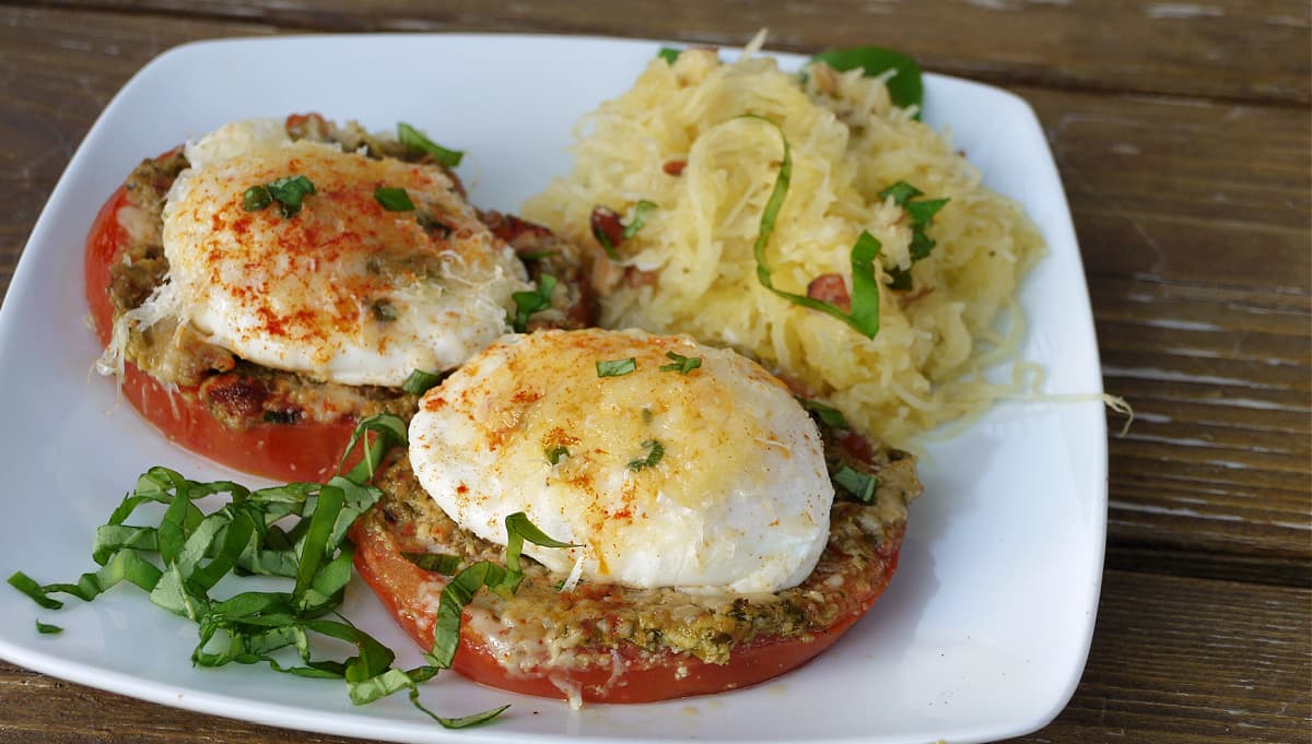 Poached eggs on top of broiled tomatoes, garnished with fresh basil ribbons.