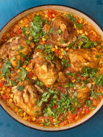 Overhead shot of cooked Arroz con Pollo in a large skillet, garnished with chopped cilantro.