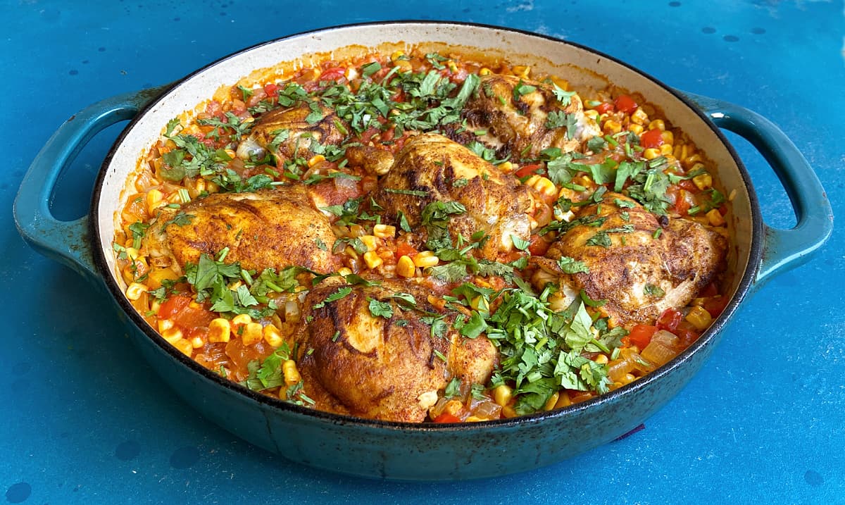 45-degree image of cooked Arroz con Pollo in a large skillet, garnished with chopped cilantro.