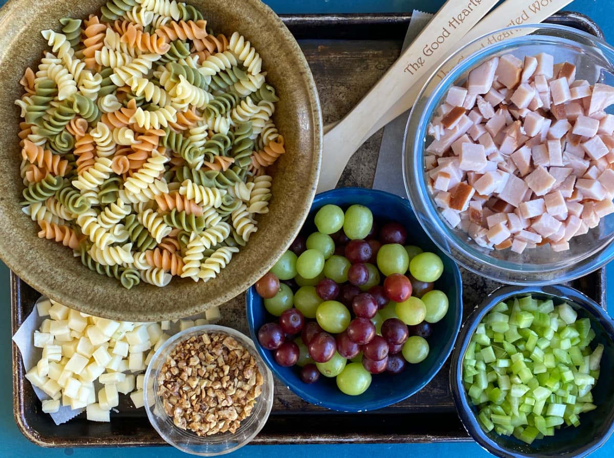 Pasta salad ingredients prepped and ready to use: spiral pasta, cubed turkey, cubed mozzarella, grapes, celery, nuts. 