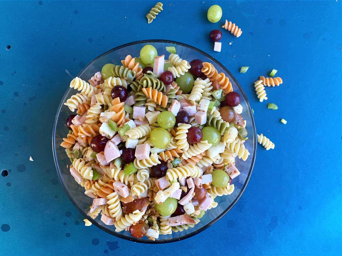 Overhead of pasta salad ingredients mixed in a bowl. 