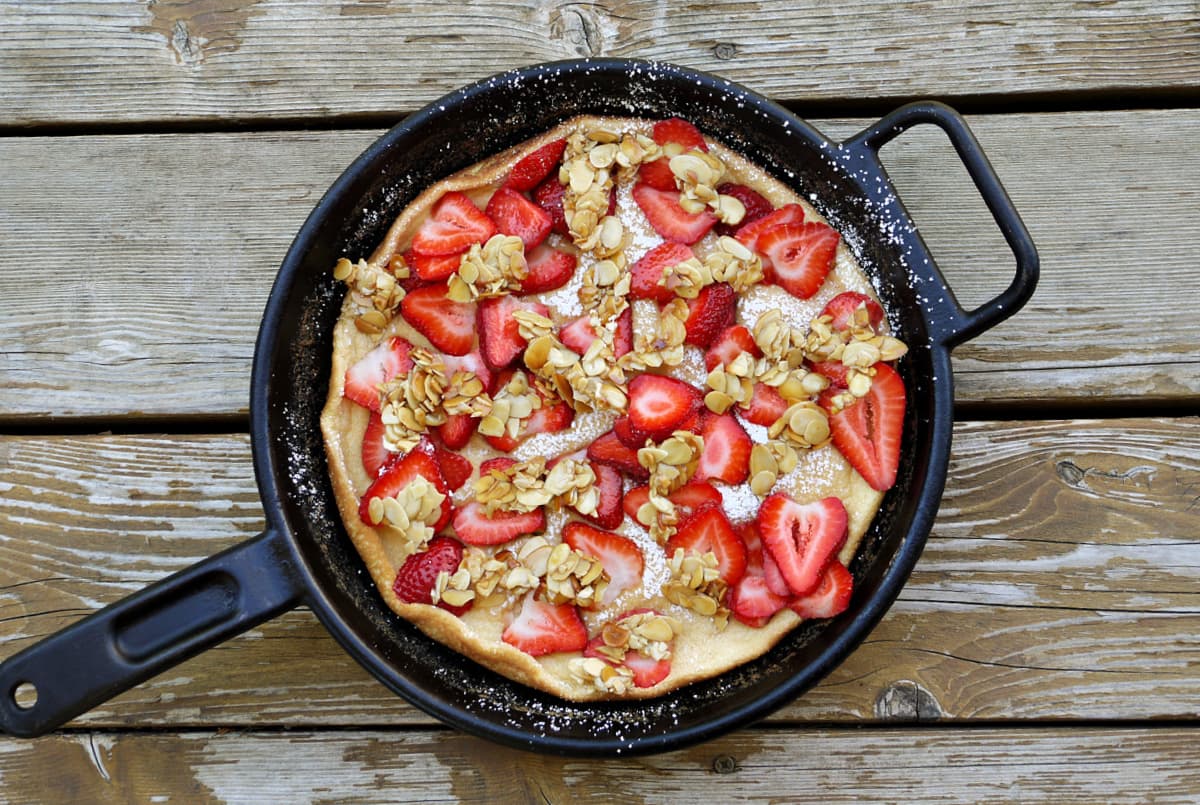 Overhead of strawberry covered omelet in cast iron skillet.